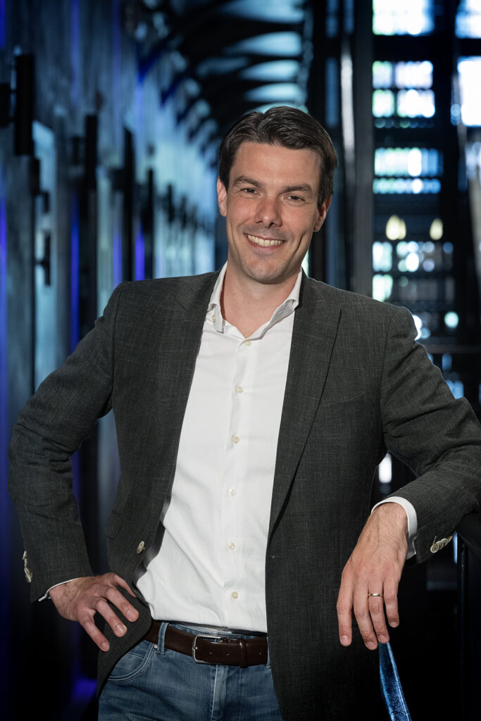 Christiaan Kwint, strafrechtadvocaat bij Knoester & Kwint Advocaten, leunend ontspannen tegen een reling in een moderne gang