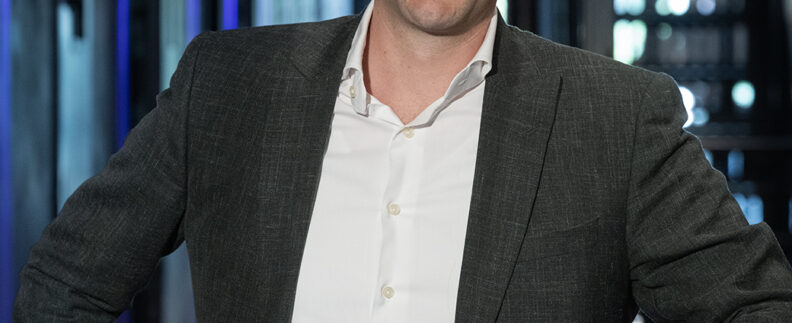 Christiaan Kwint, strafrechtadvocaat bij Knoester & Kwint Advocaten, leunend ontspannen tegen een reling in een moderne gang