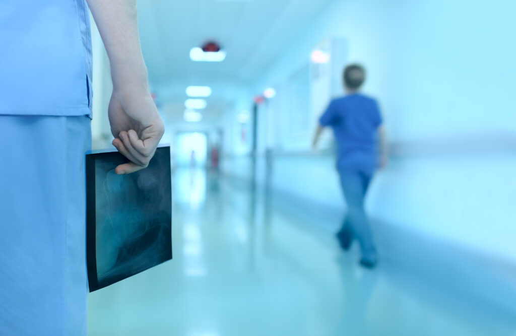 Verpleegkundige in ziekenhuisgang met röntgenfoto in de hand, symbool voor zorg en uitzichtloosheid binnen tbs-klinieken